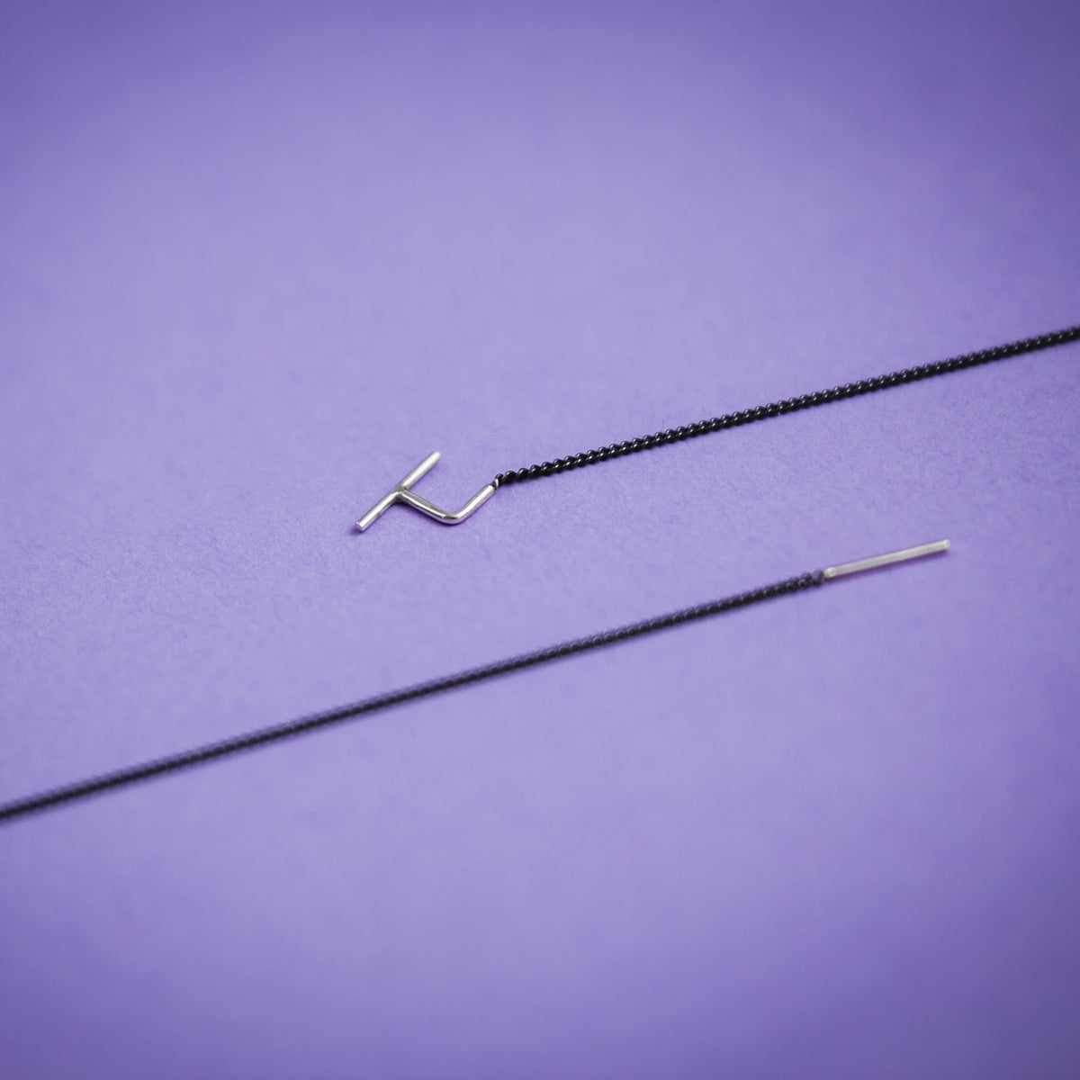 3. Close-up of Maarja Palu SWING 2 earrings on purple background, highlighting sleek design