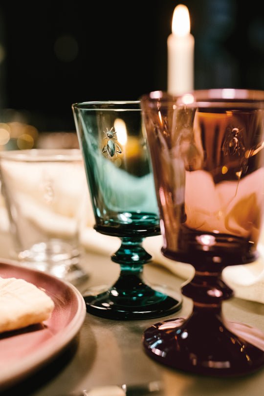 10. Close-up of La Rochère Bee Glasses in blue and purple on a candlelit table setting