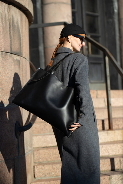 2. Woman wearing PYKOK Adele large black leather handbag over shoulder, urban background