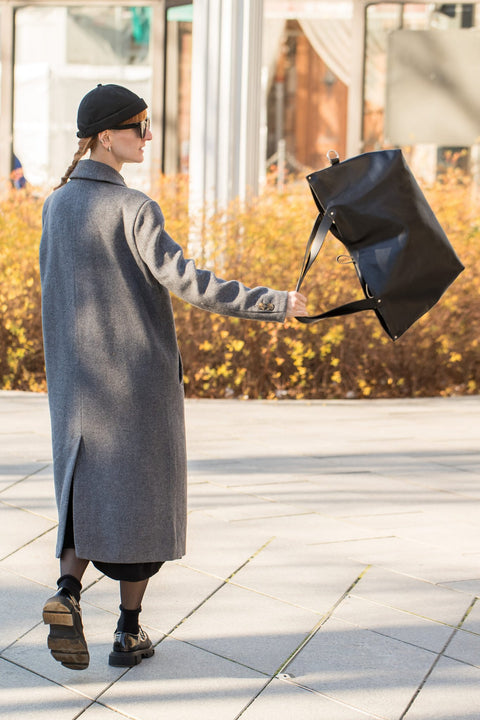 4. Woman swinging PYKOK Large Handbag Lima in soft black leather, demonstrating lightweight and spacious design