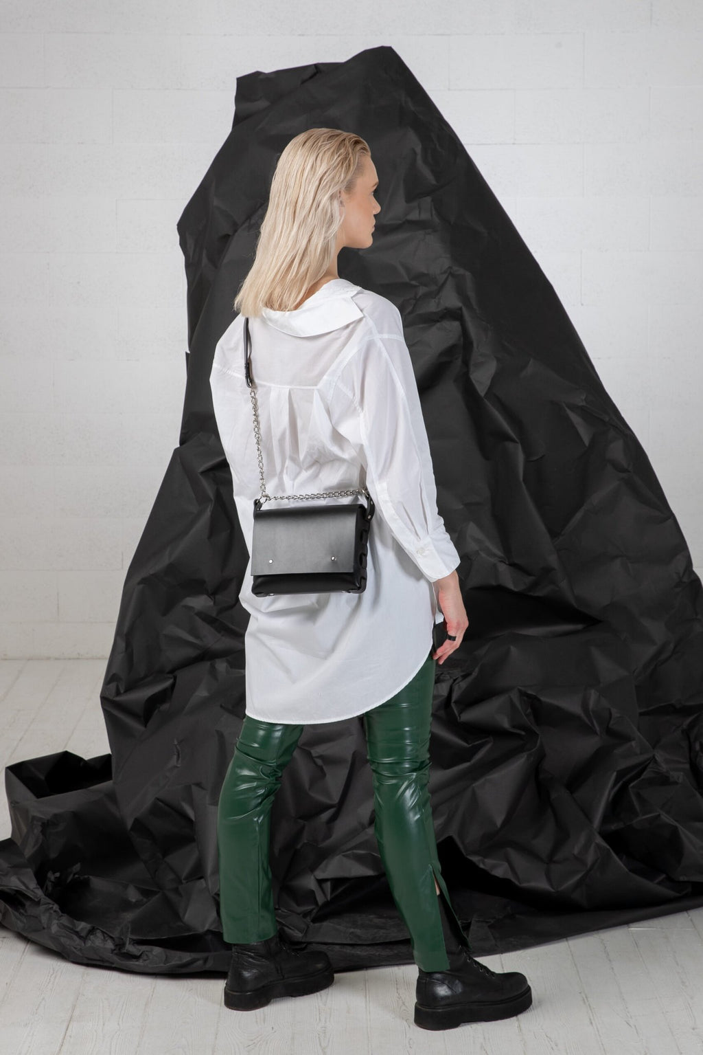 1. Woman wearing PYKOK Agatha no.3 handbag with chain strap, styled with white shirt and green pants, studio setting