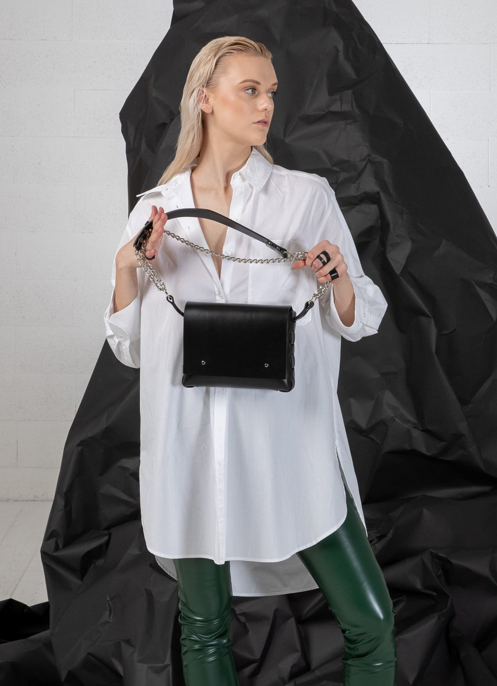 3. Woman holding PYKOK Agatha no.3 handbag with chain and leather strap, styled with white shirt, studio setting
