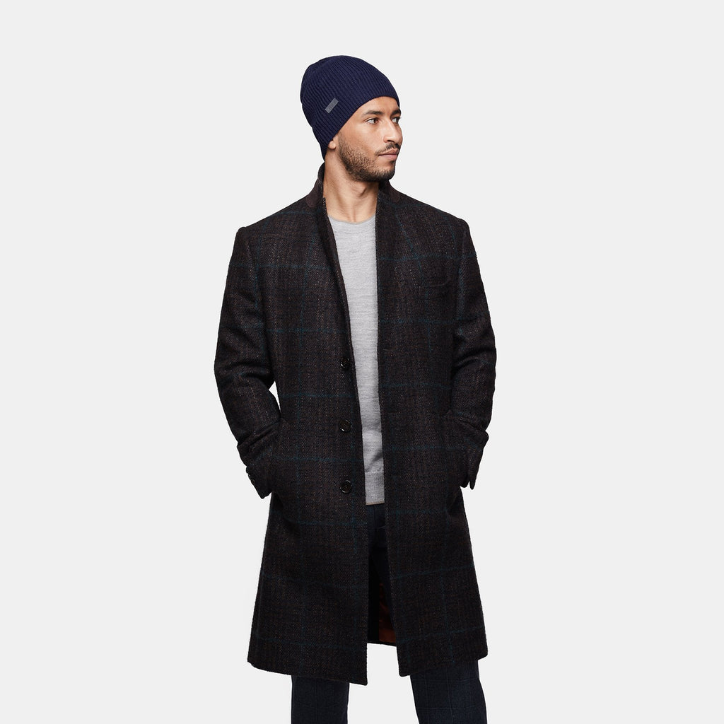 9. Man wearing navy Alpaka baby alpaca wool fisherman's rib beanie with dark coat, hands in pockets