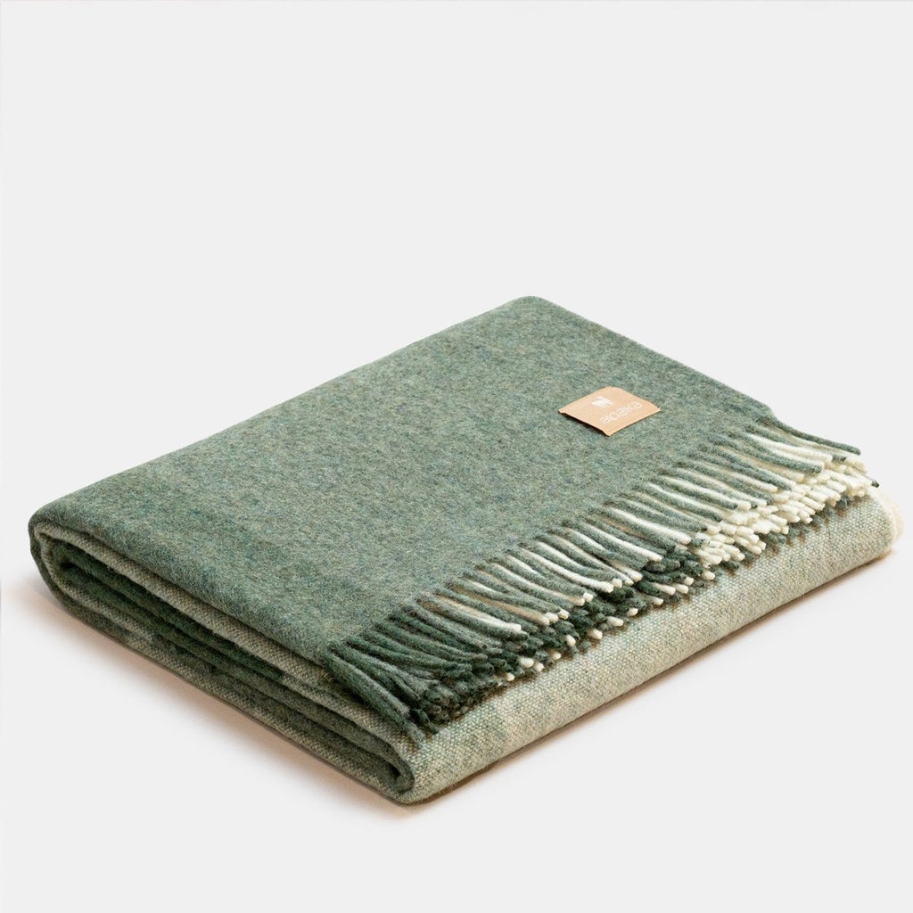 4. Studio image of green Recycled Alpaca Wool Throw with classic check pattern and fringe detail