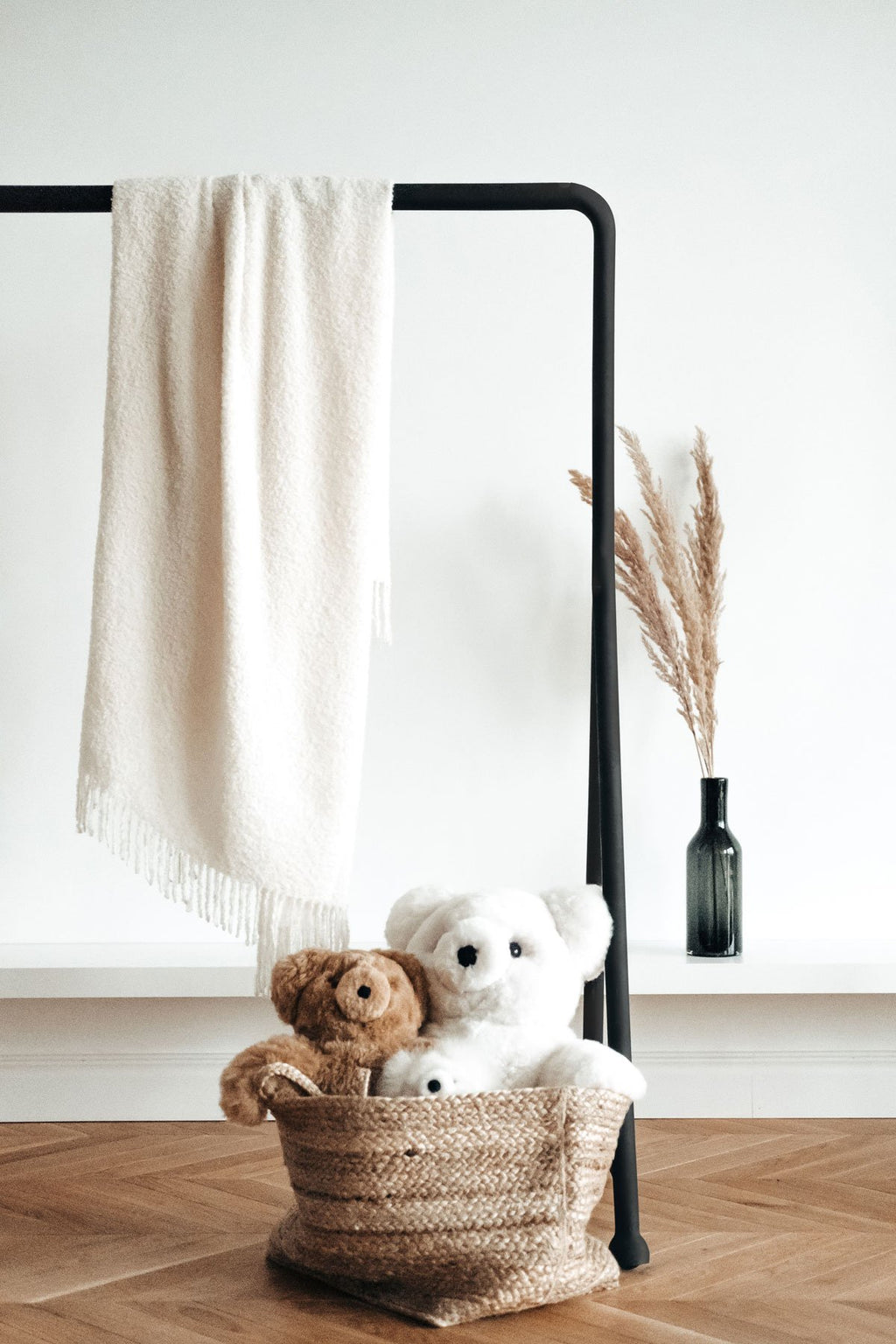 1. Luxurious white superfine alpaca wool boucle throw draped over a black stand, styled with plush toys in a basket, enhancing cozy home decor