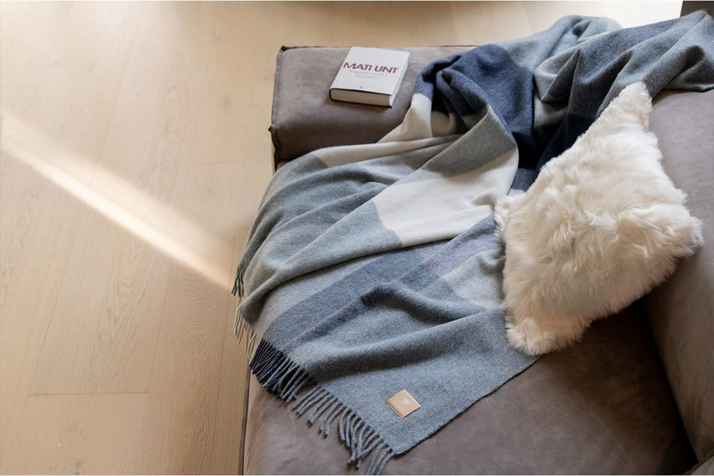 1. Recycled Alpaca Wool Throw in classic check pattern draped over a sofa, showcasing its luxurious texture and Nordic-inspired design