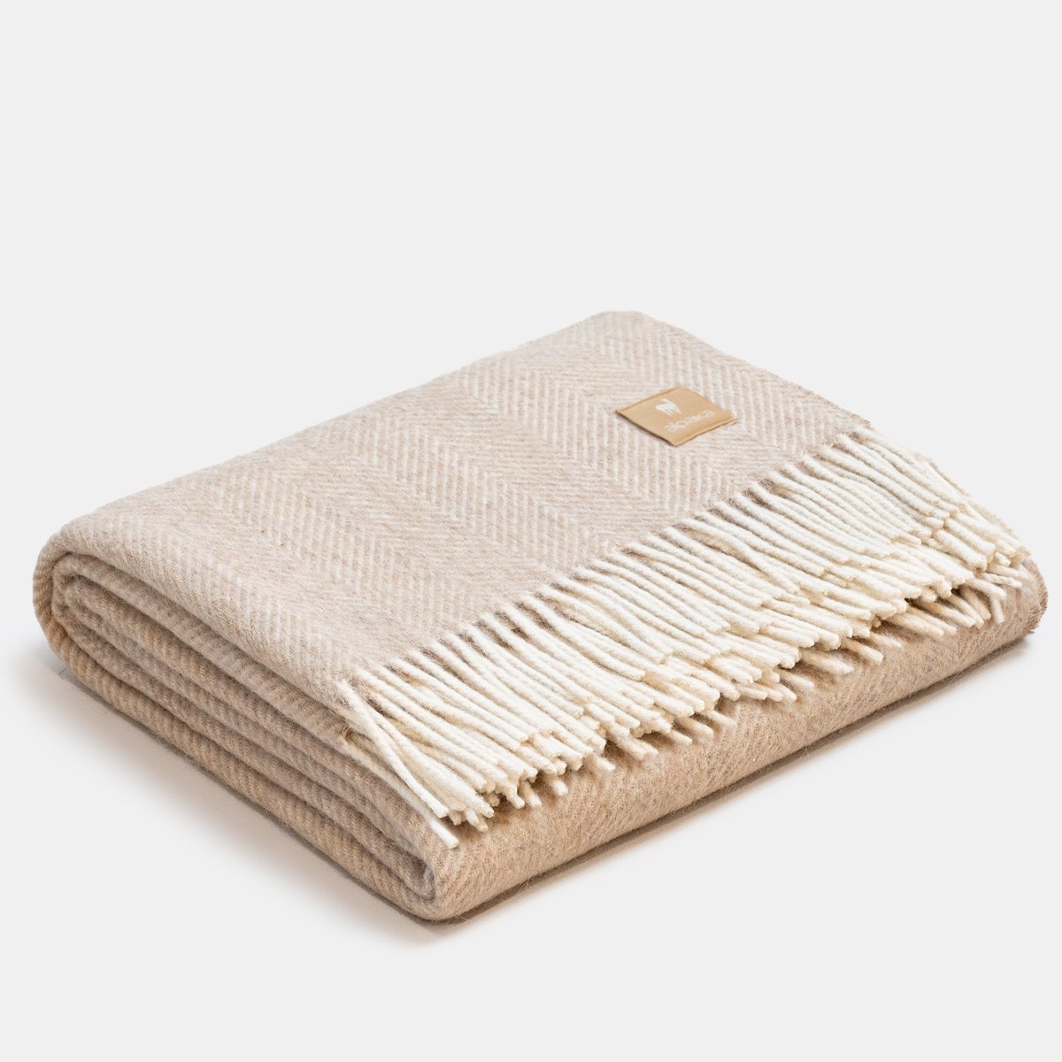 7. Folded beige Alpaka wool throw with fishbone pattern and fringe in studio