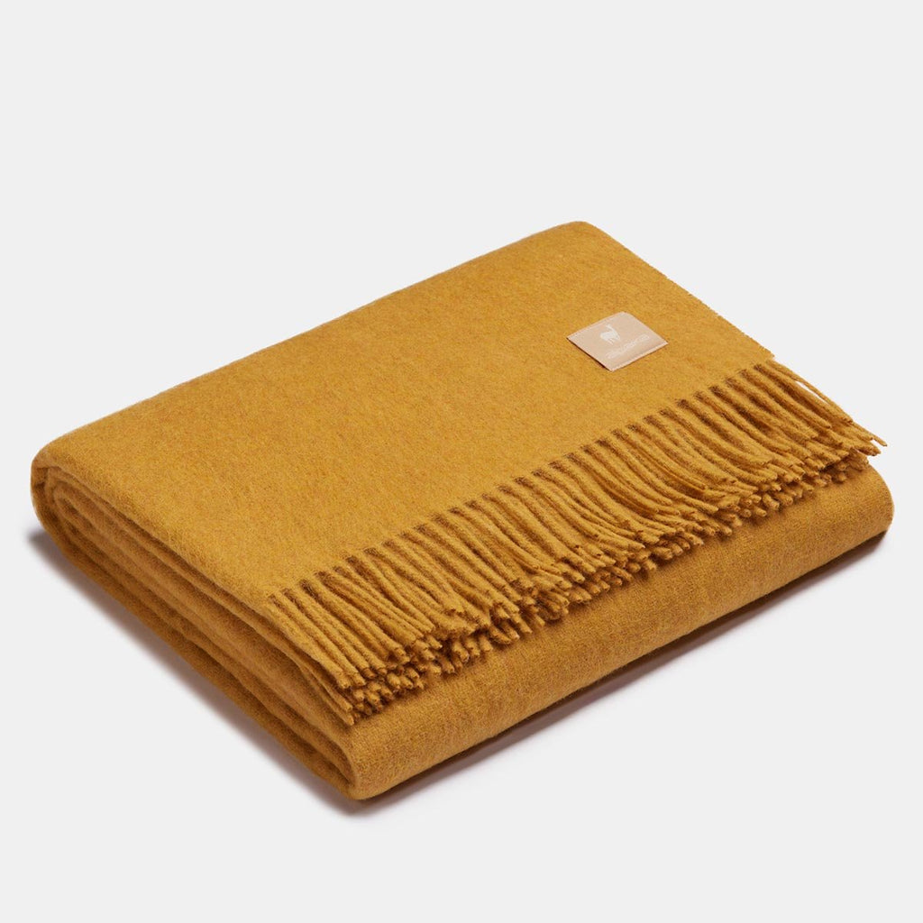 2. Mustard Alpaka natural alpaca wool throw with fringe detail, folded in studio
