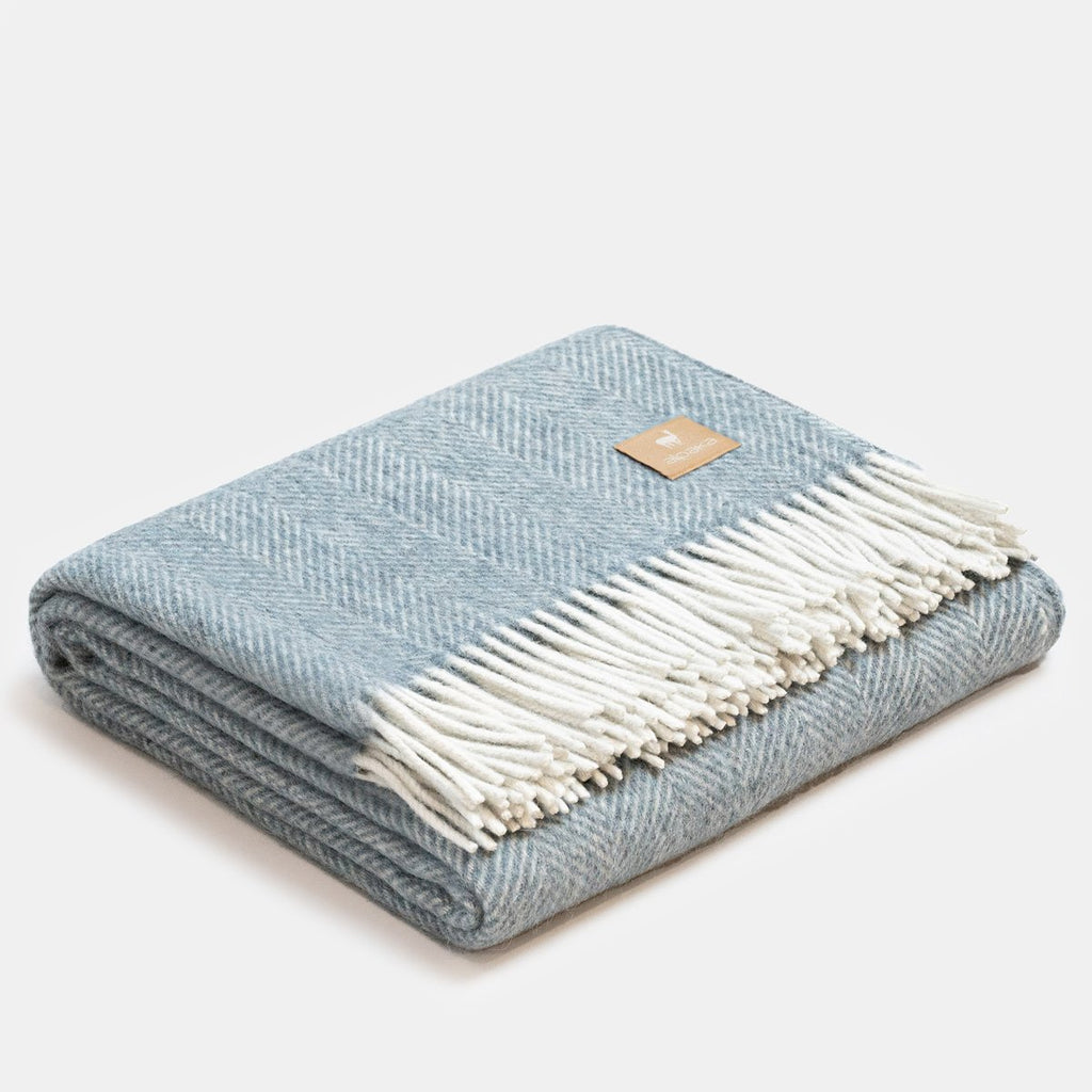 8. Folded blue Alpaka wool throw with fishbone pattern and fringe in studio