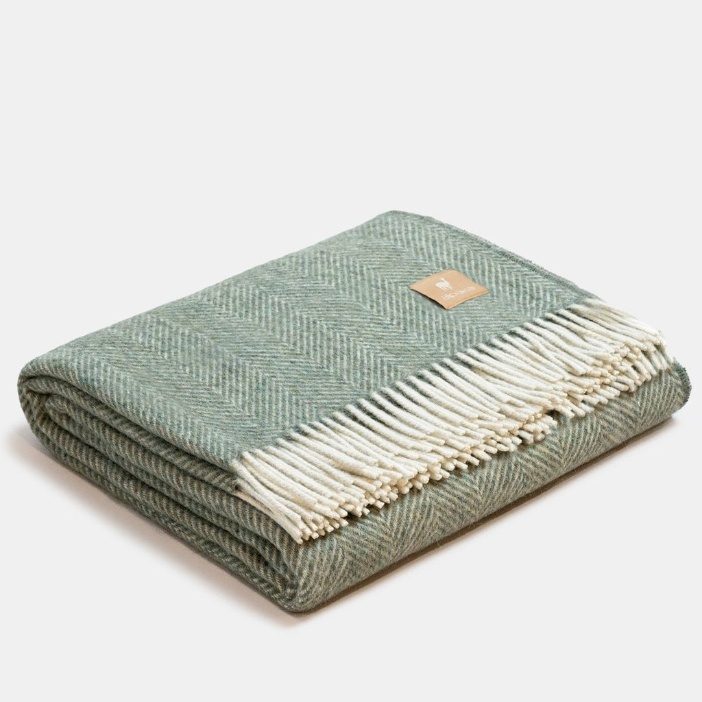 2. Folded green Alpaka wool throw with classic fishbone pattern and fringe detail in studio