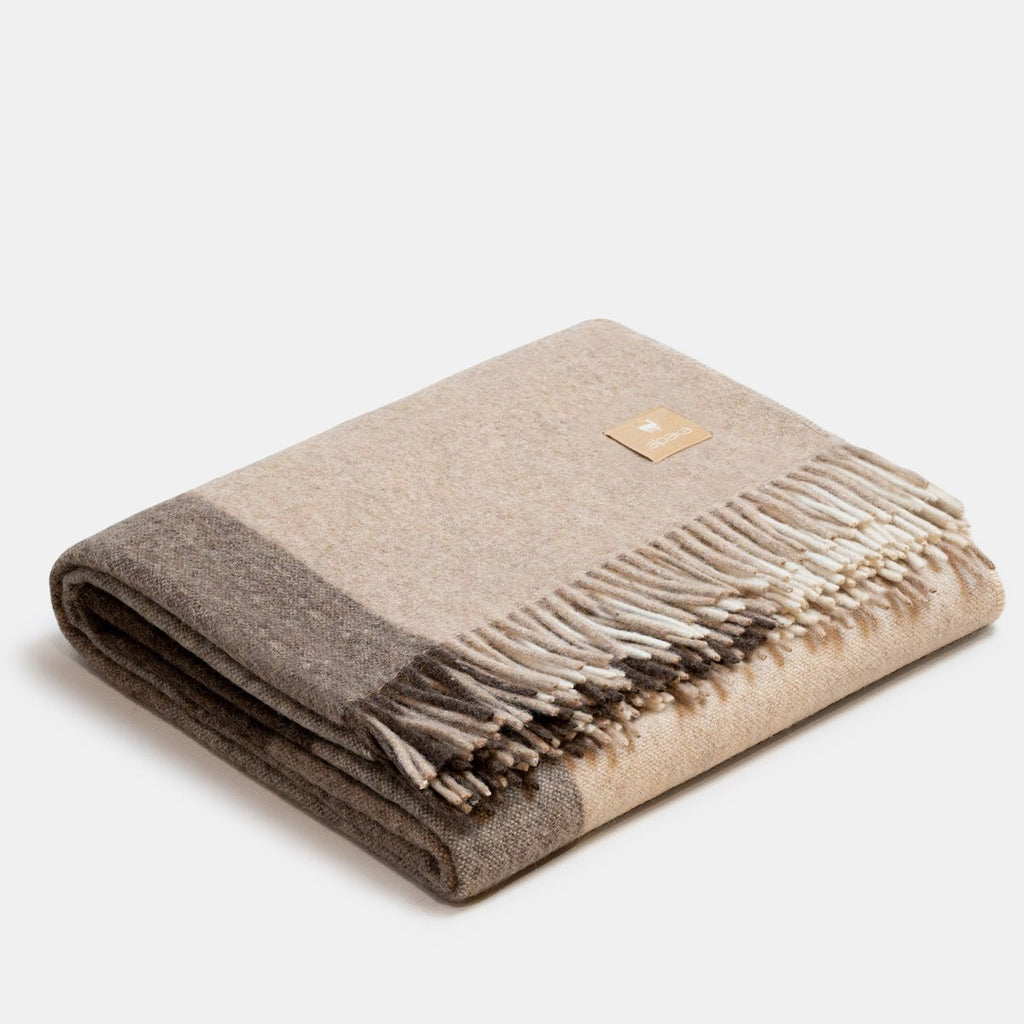 7. Studio image of beige Recycled Alpaca Wool Throw with classic check pattern and fringe detail