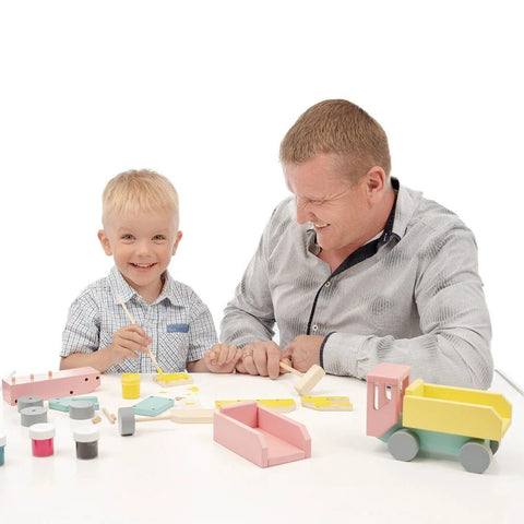 1. Father and son assembling and painting Adensen Villi wooden truck at a table, engaging in creative play