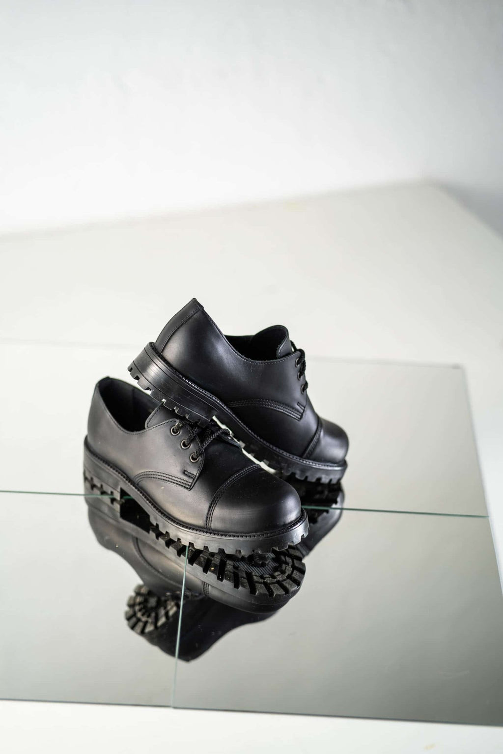 5. Studio shot of unisex black Samelin Widgets on reflective surface, highlighting sole and side