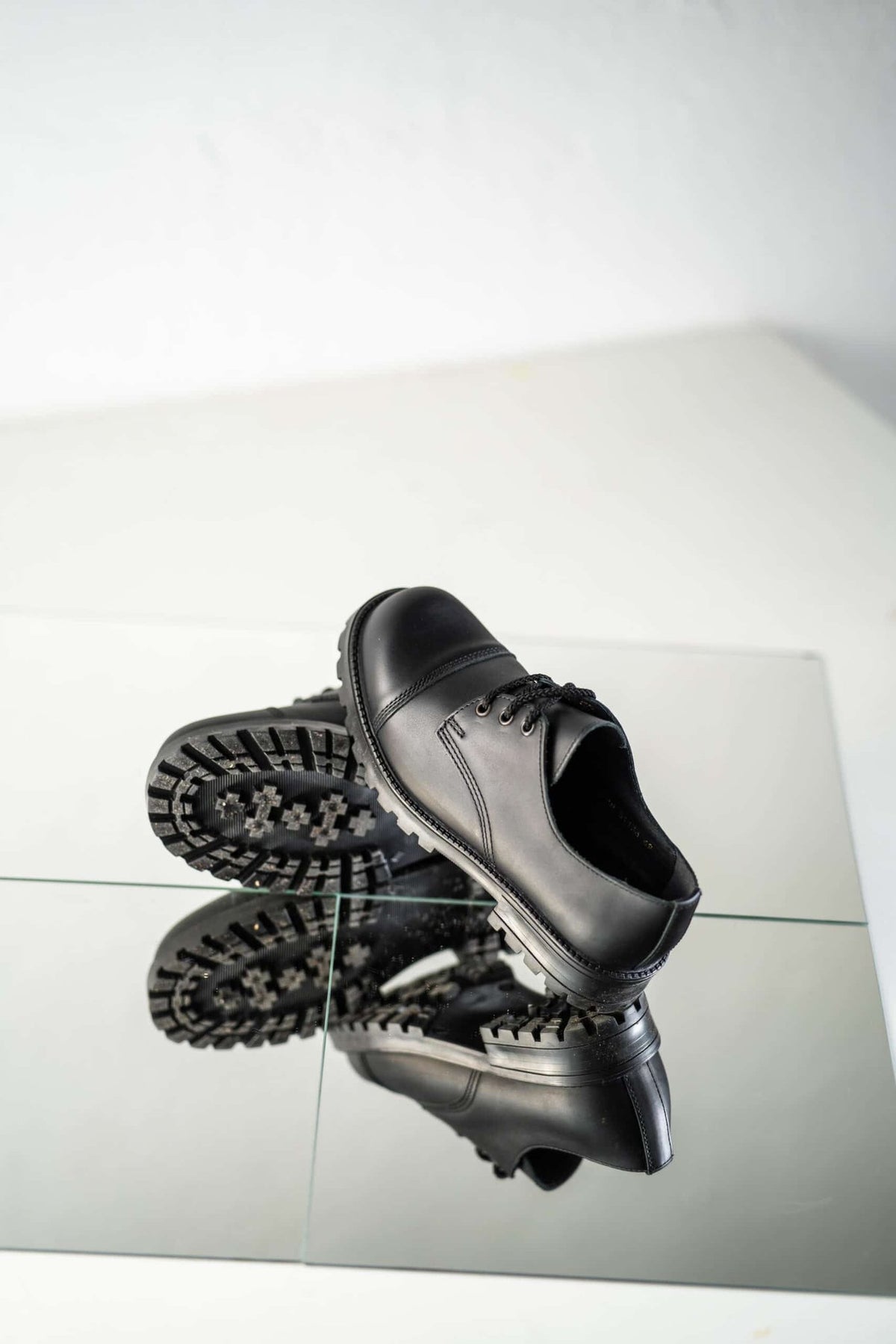 6. Studio shot of unisex black Samelin Widgets on reflective surface, showing sole and top view