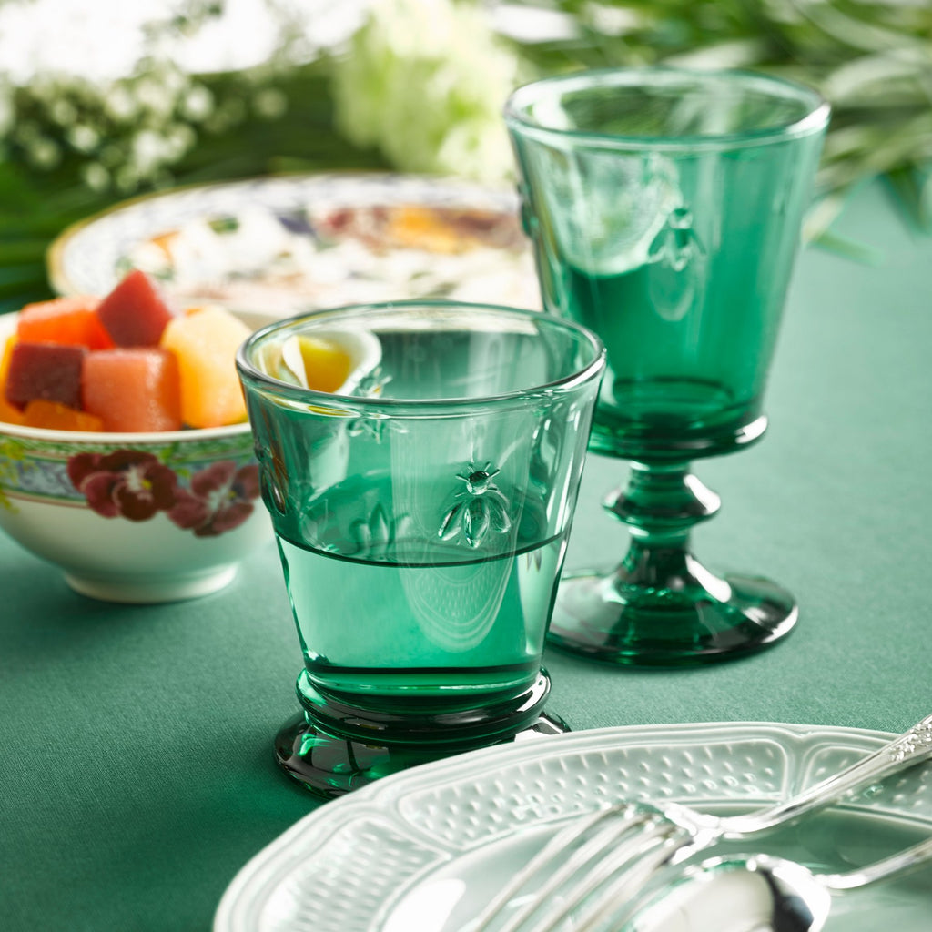 7. Two La Rochère Bee Water Glasses in emerald on a green table setting with fruit bowl and plate