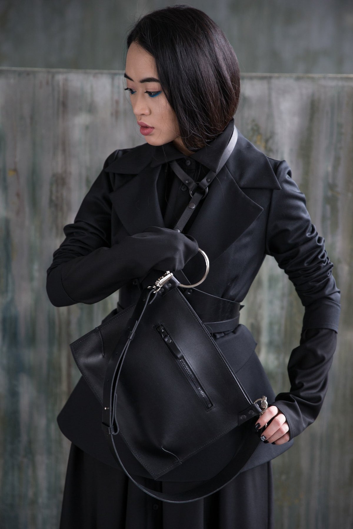 2. Woman wearing PYKOK Serenity black leather handbag, showcasing sleek design and compact size