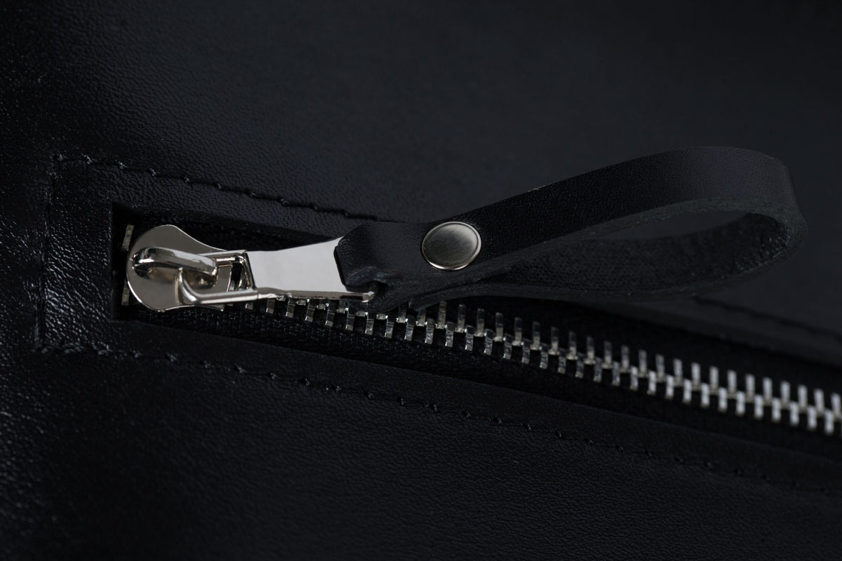 5. Close-up of PYKOK Serenity handbag's front zipper and leather pull tab