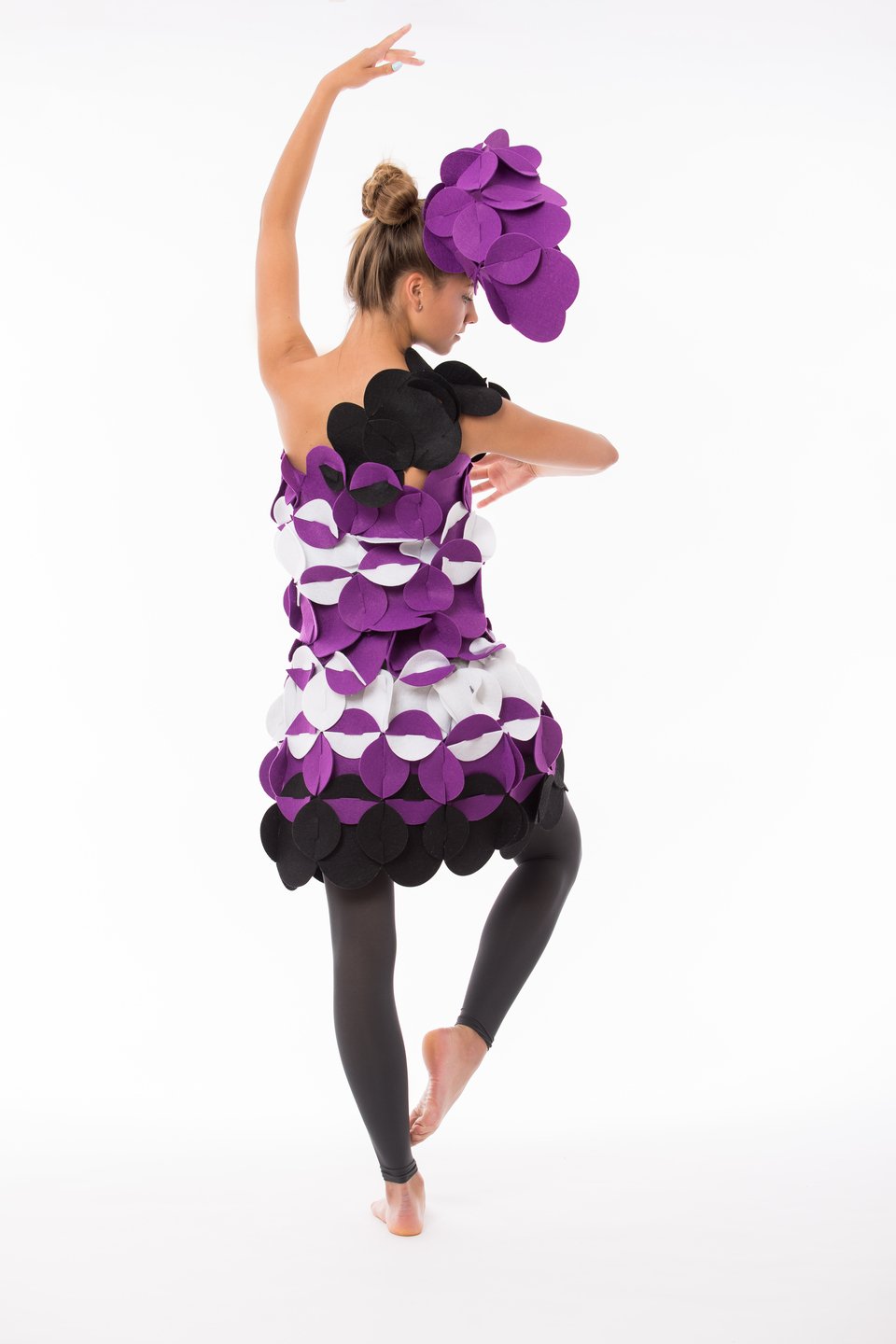 2. Woman in purple and black felt costume with floral headpiece posing as ballerina on white background