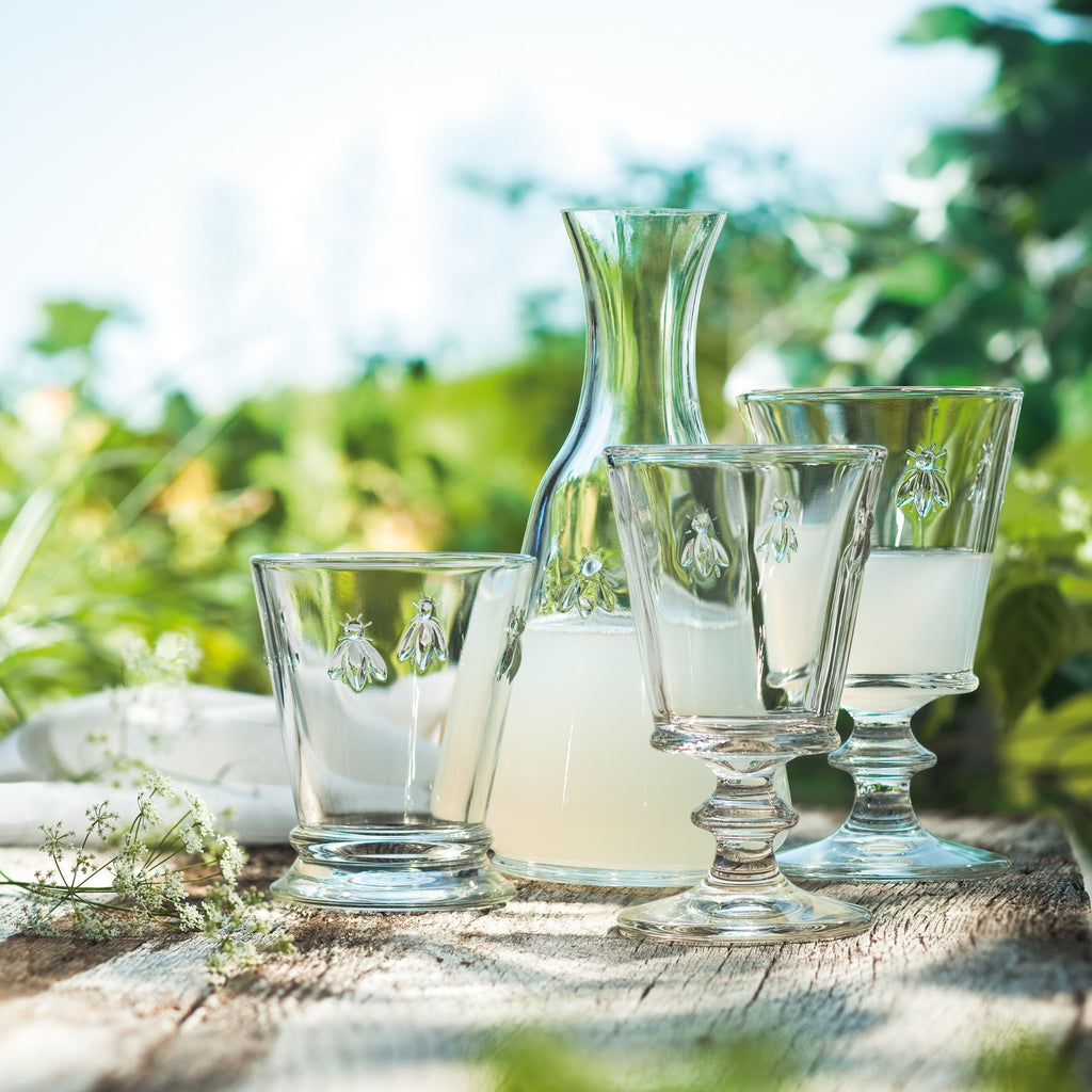 5. La Rochère Bee glass set with carafe on a rustic table in a garden setting