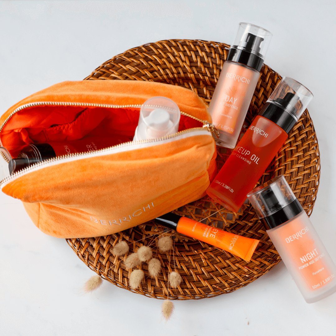 1. Berrichi Cosmetic Bag in orange with beauty products, shown on a woven mat