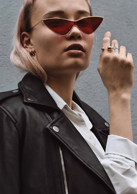 4. Woman wearing NO MORE Big Bomb Multisize Ring in gold, styled with red sunglasses and a leather jacket