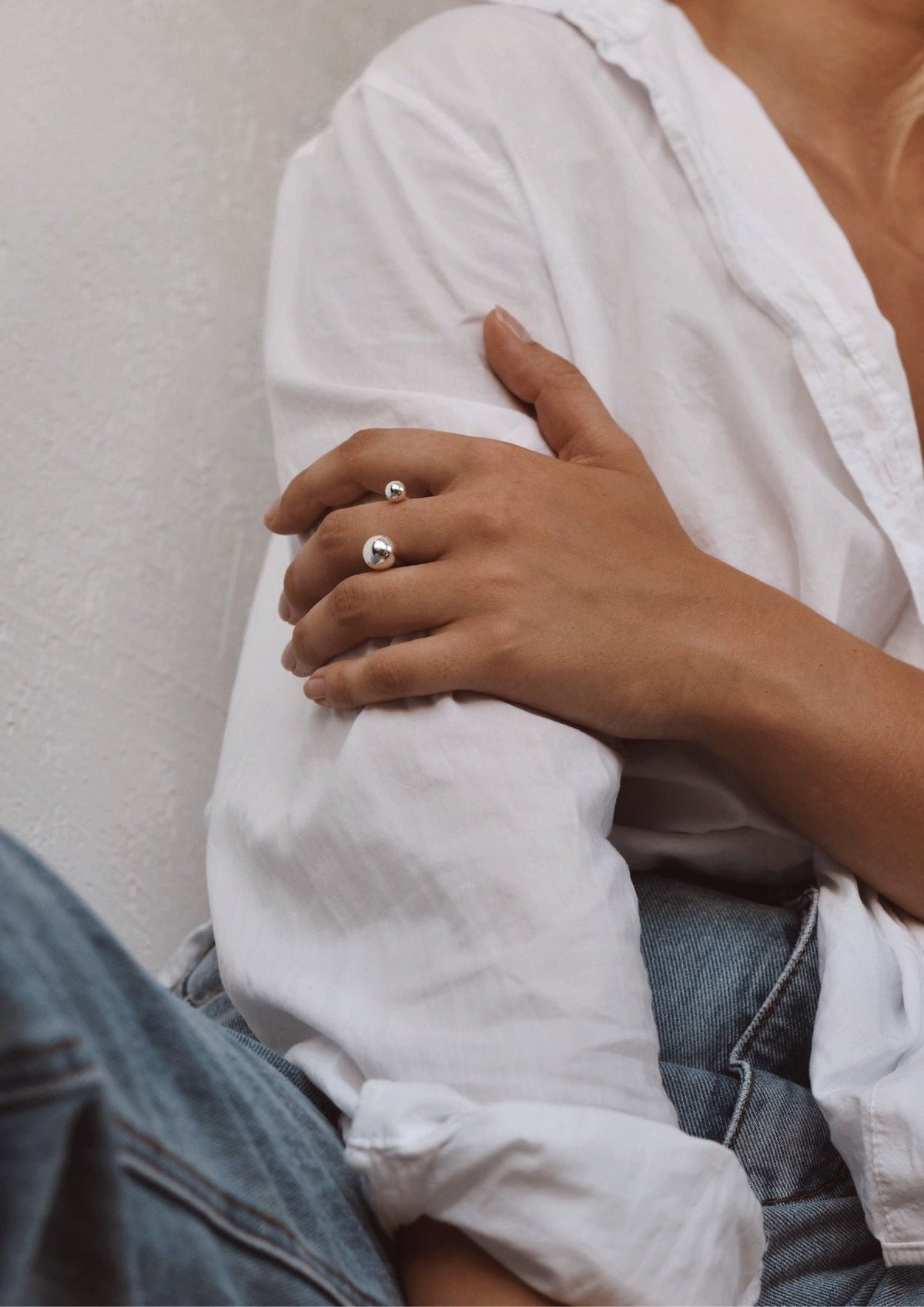 6. Woman wearing NO MORE Big Bomb Multisize Ring in silver, paired with a white shirt and jeans, showcasing casual chic style