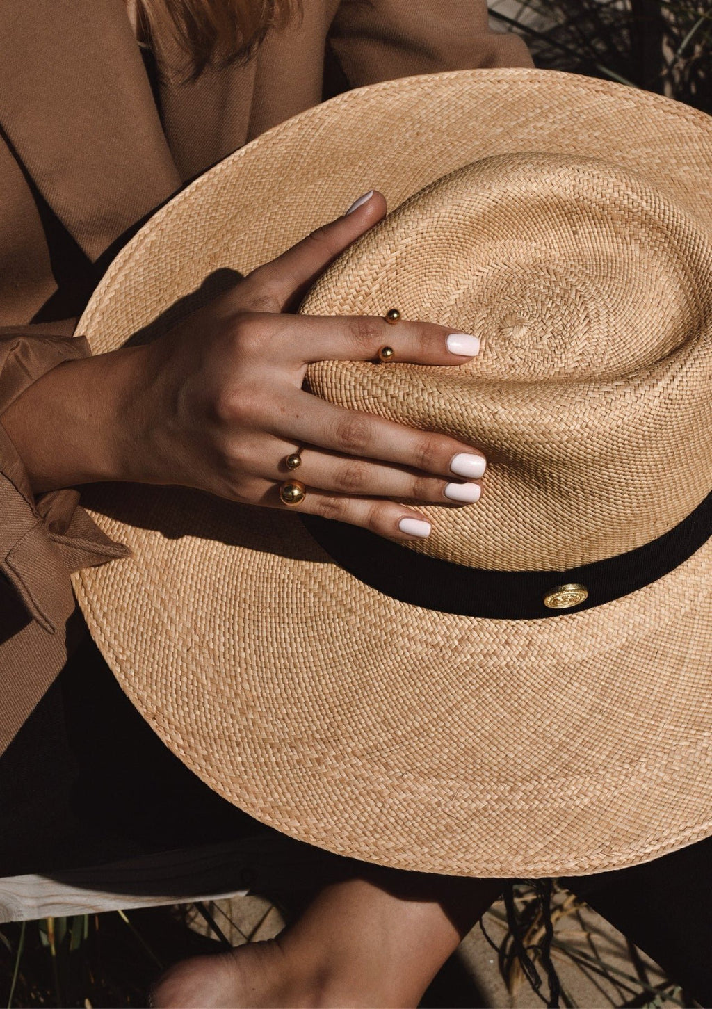 1. Women's hand wearing NO MORE Big Bomb Multisize Ring in gold, holding a straw hat, showcasing adjustable bubble design