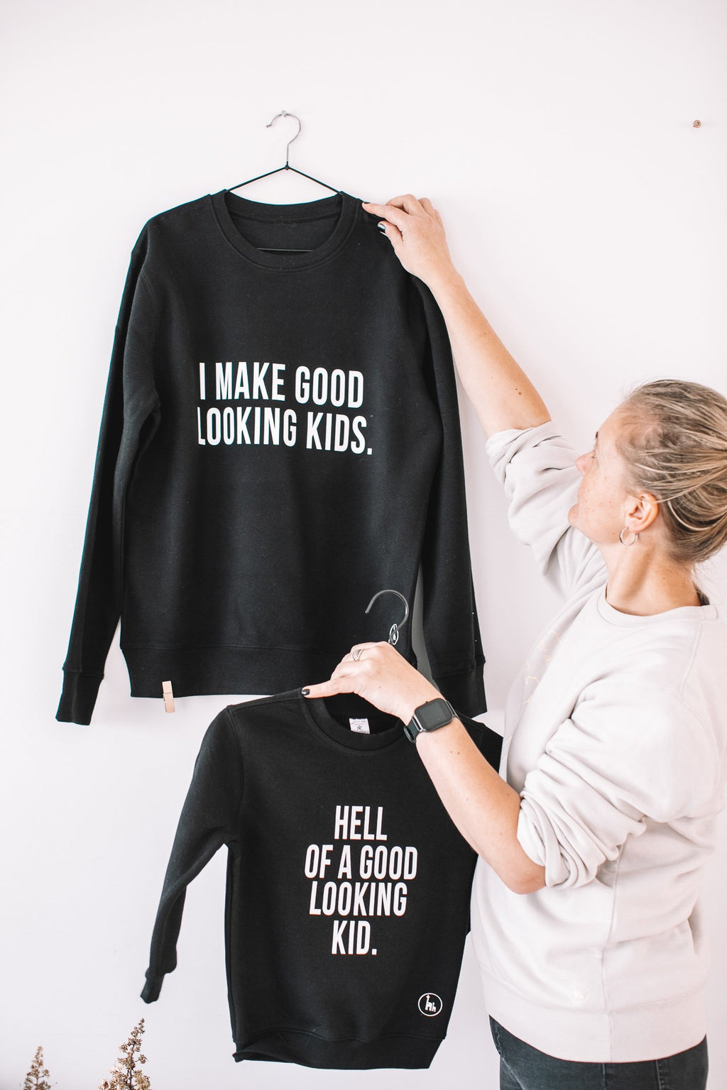 5. Flat lay of Black Giraffe Brand matching black sweatshirts for dad and child, featuring 'I Make Good Looking Kids' and 'Hell of a Good Looking Kid' text, displayed on hangers