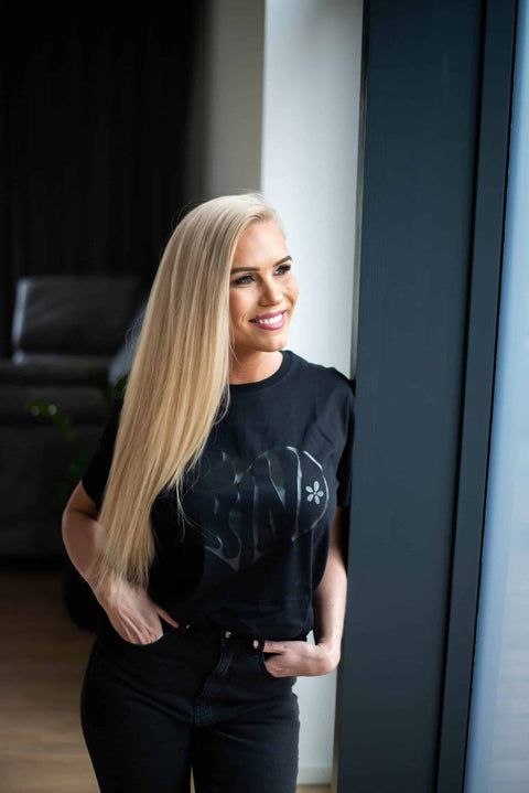 2. Woman smiling in Black Giraffe Brand Be Kind T-shirt, showcasing oversized fit and minimalist design in lifestyle setting