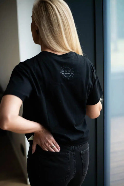 3. Back view of woman wearing Black Giraffe Brand Be Kind T-shirt, highlighting hidden message and relaxed fit