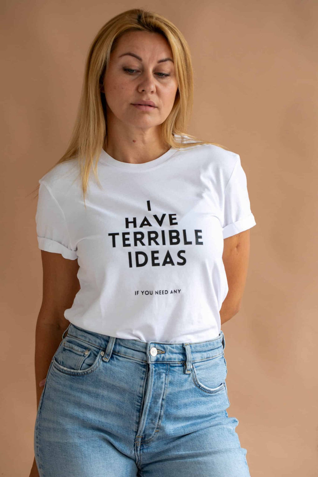 2. Women's white 'I Have Terrible Ideas' t-shirt by Black Giraffe Brand, styled with rolled-up sleeves, worn by model standing