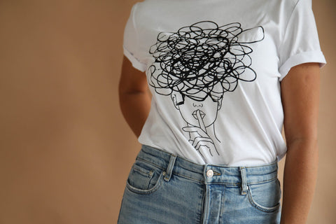5. Close-up of women's white Šššhhh! T-shirt by Black Giraffe Brand, highlighting abstract face design and rolled-up sleeves