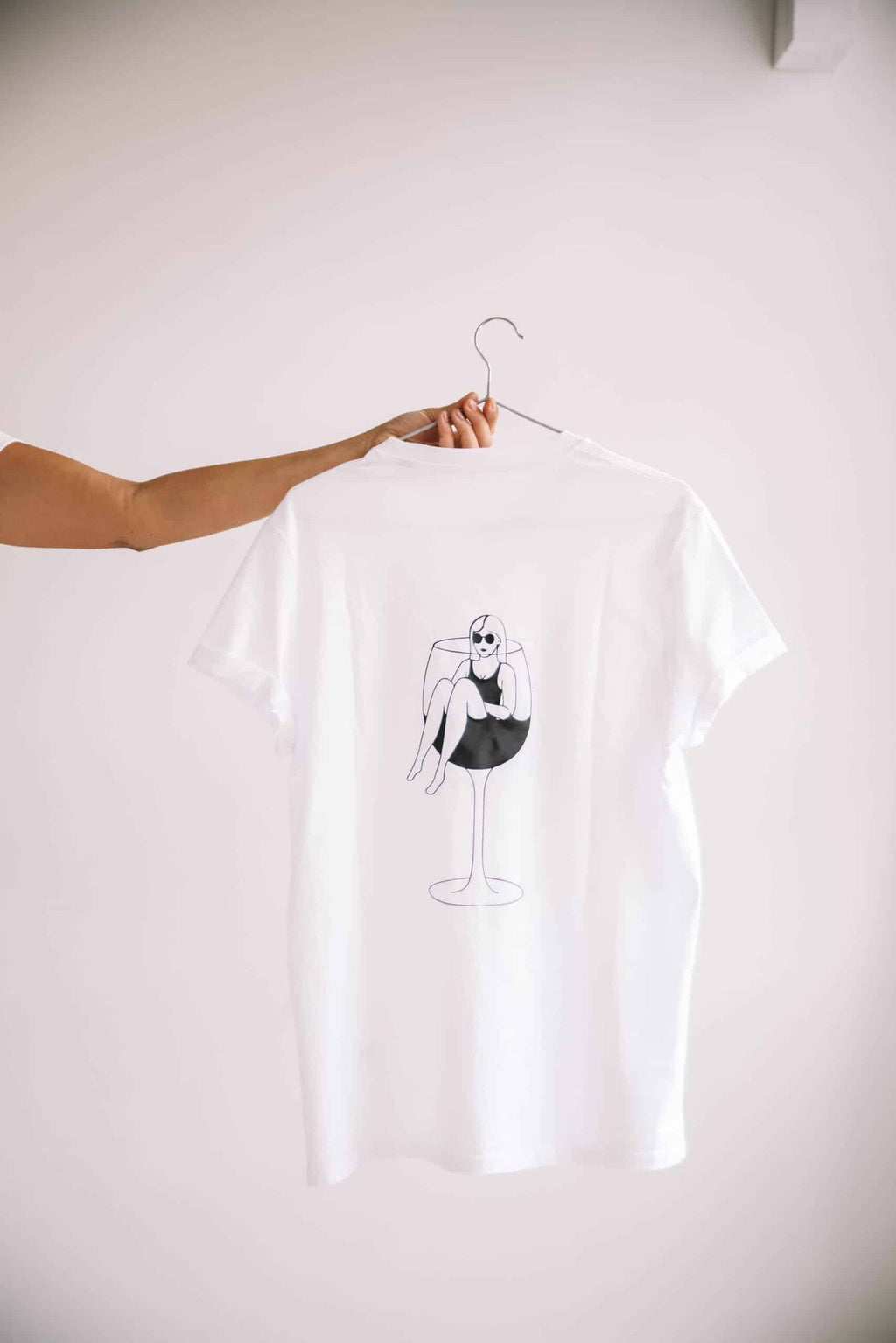 4. Studio shot of white T-shirt by Black Giraffe Brand, highlighting wine glass illustration on back