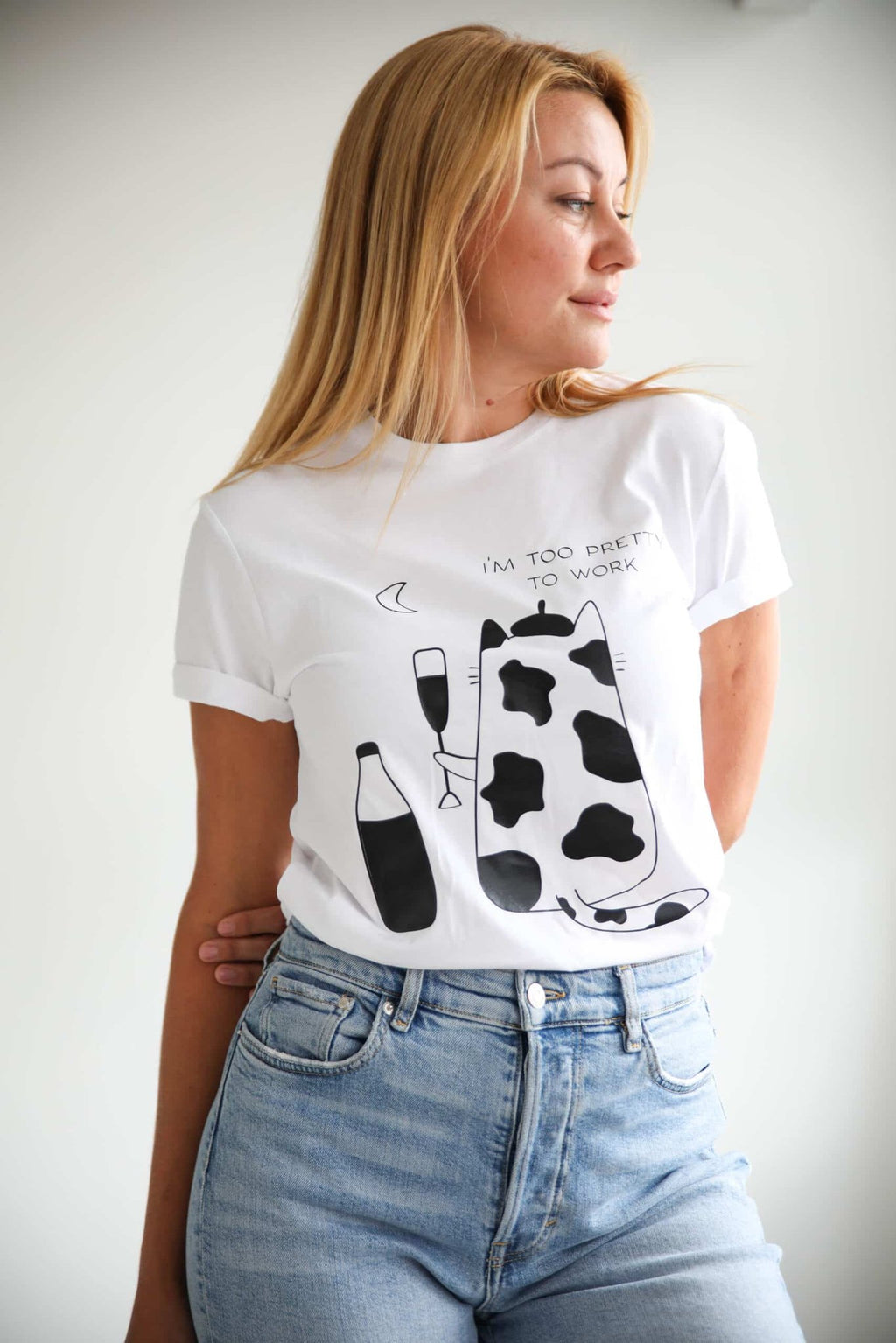 1. Women's white 'Too Pretty To Work' T-shirt by Black Giraffe Brand, worn by model with rolled-up sleeves, featuring playful graphic design