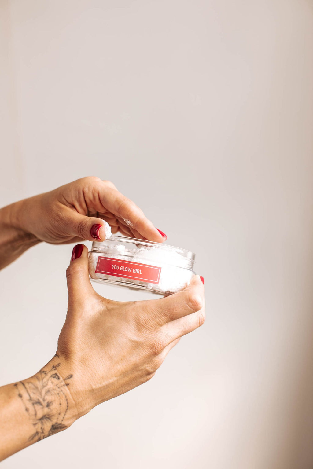 7. Close-up of Black Giraffe Brand Exfoliating Shower Cream with 'You Glow Girl' label, being opened