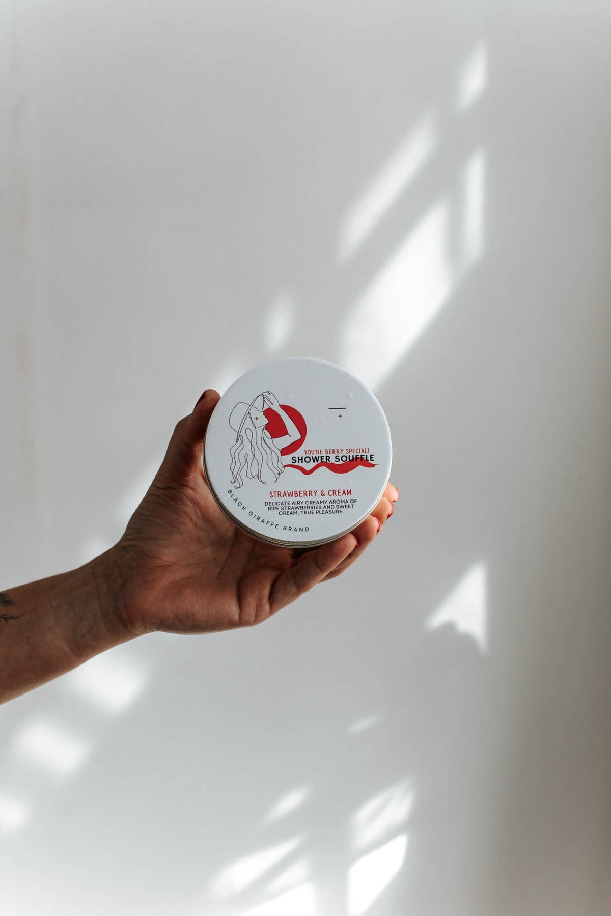 8. Black Giraffe Brand Exfoliating Shower Cream in hand, highlighting Strawberry & Cream scent packaging