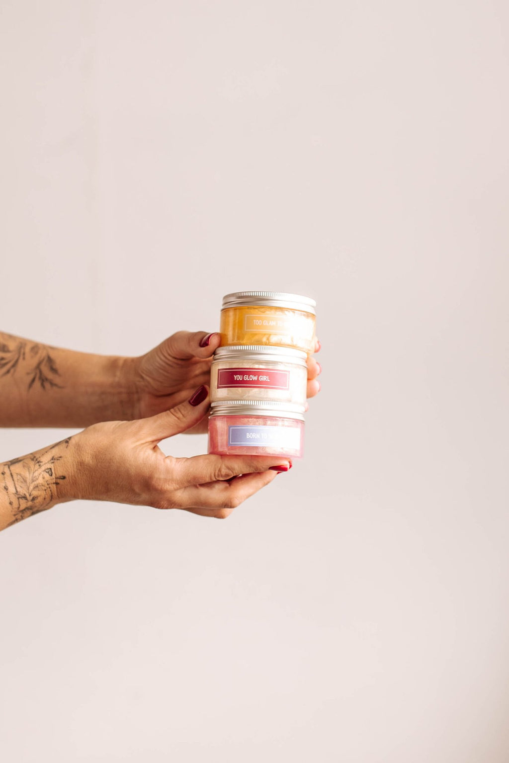 4. Hands holding stack of Black Giraffe Brand Sparkling Body Gel jars in various scents