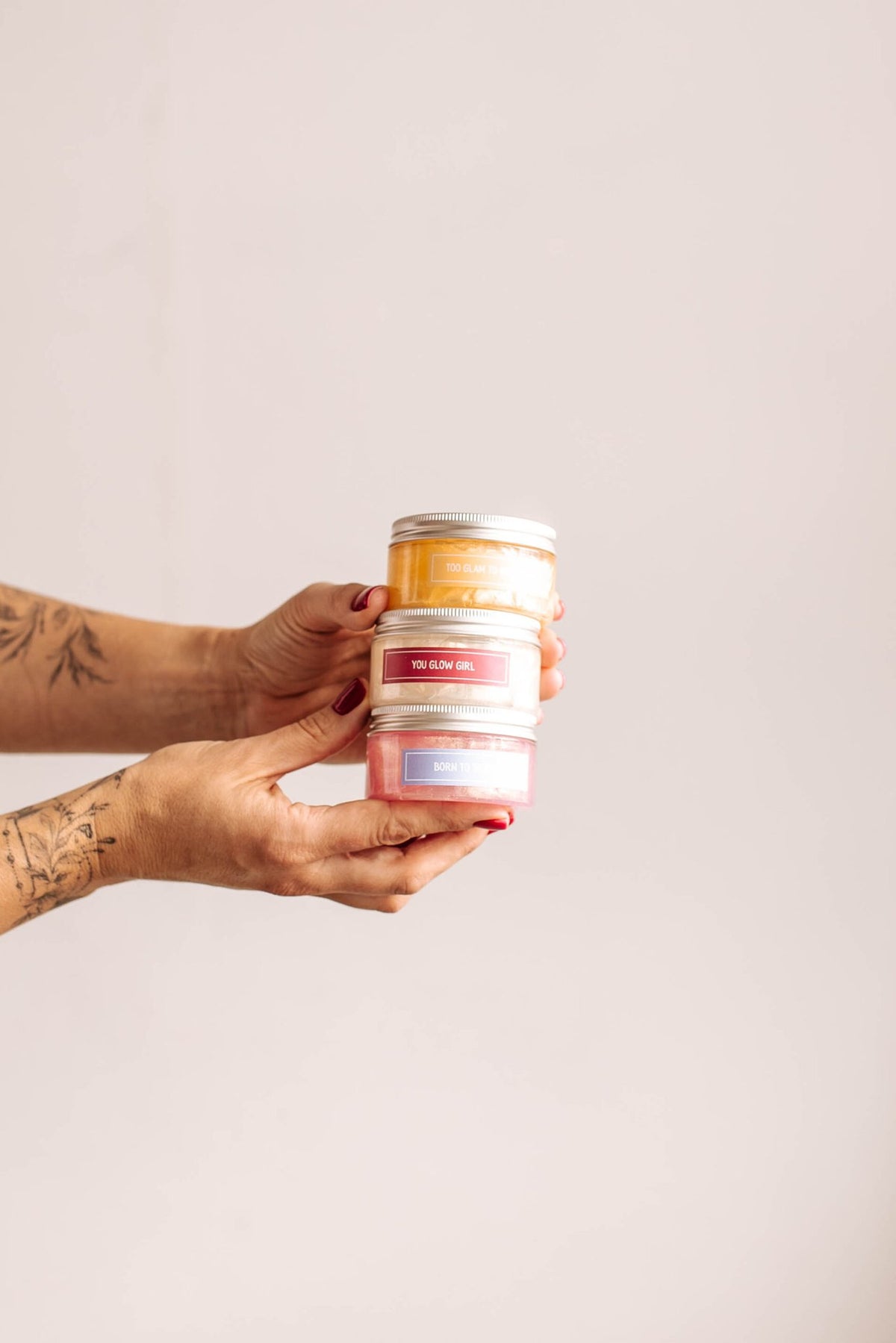 4. Hands holding stack of Black Giraffe Brand Sparkling Body Gel jars in various scents