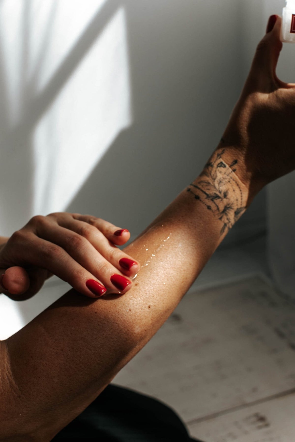 1. Woman applying Black Giraffe Brand Sparkling Body Gel on arm, showcasing shimmer effect