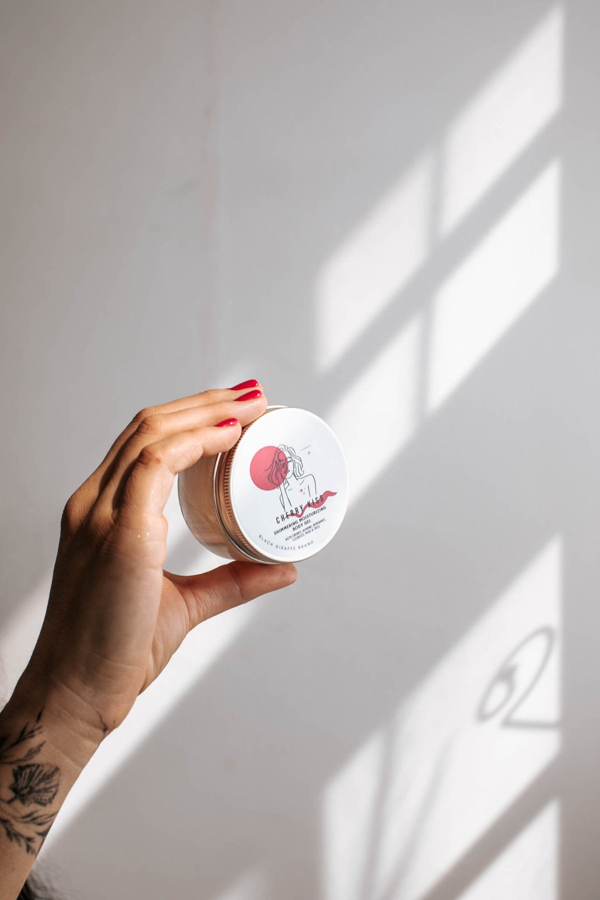 6. Hand holding Black Giraffe Brand Sparkling Body Gel jar, focusing on product lid design