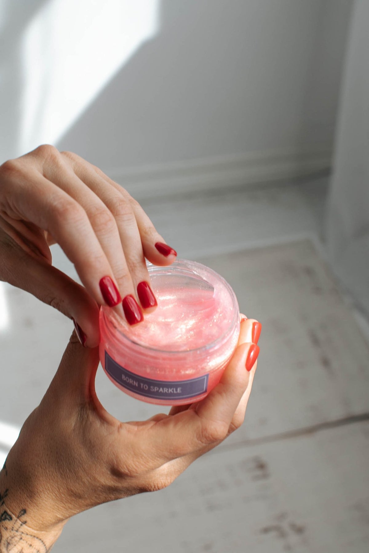 7. Close-up of hand dipping into Black Giraffe Brand Sparkling Body Gel, showing pink gel