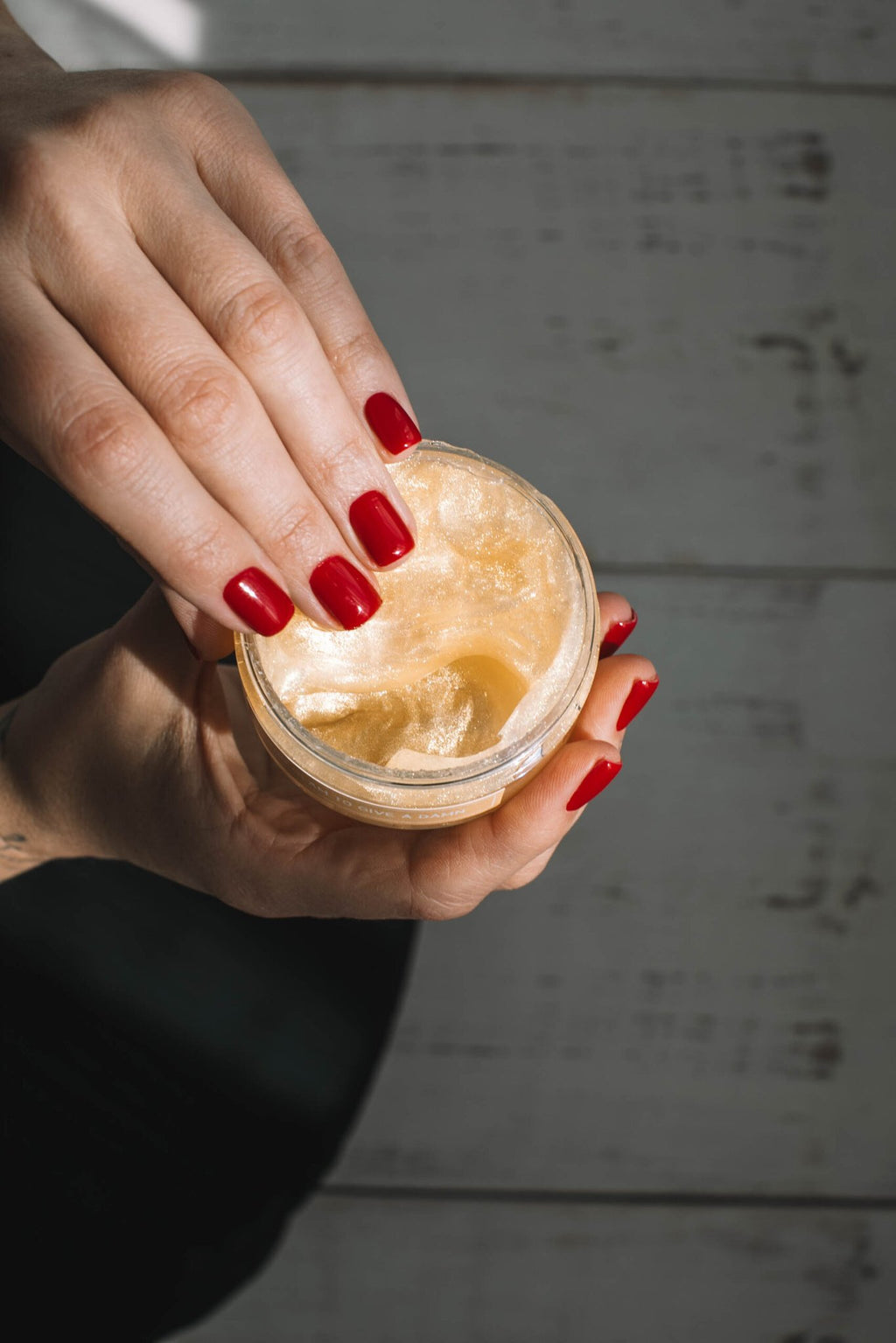 3. Close-up of hands opening Black Giraffe Brand Sparkling Body Gel jar, showing shimmering gel