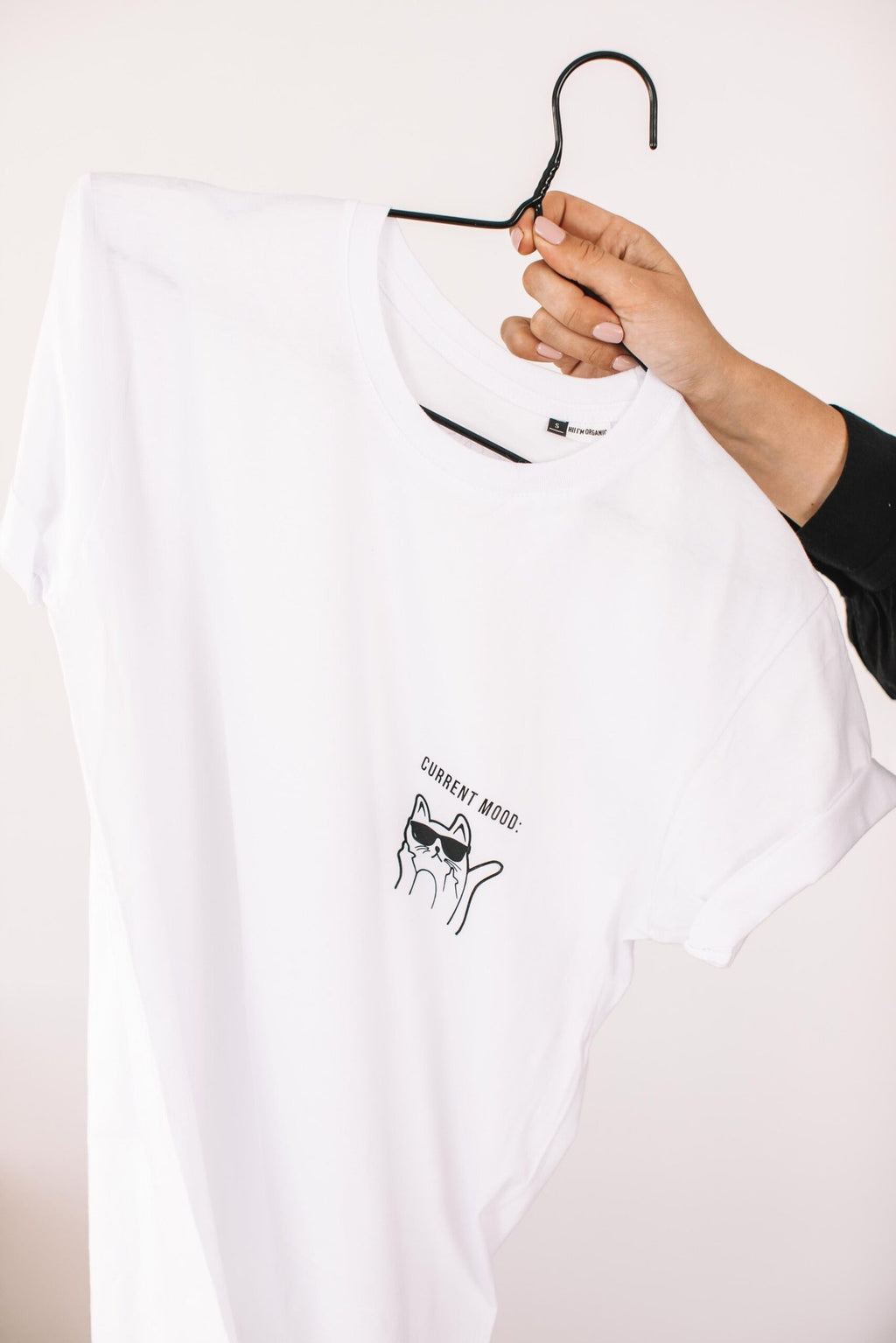 4. Studio shot of white Current Mood T-Shirt with kitty design by Black Giraffe Brand, held on hanger