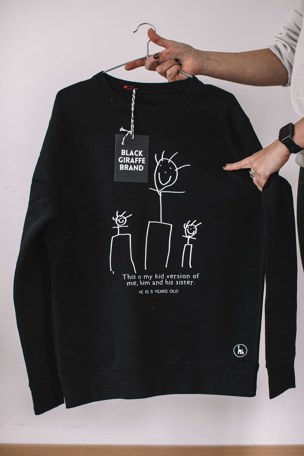 7. Black sweatshirt featuring child's drawing, Black Giraffe Brand, displayed in studio