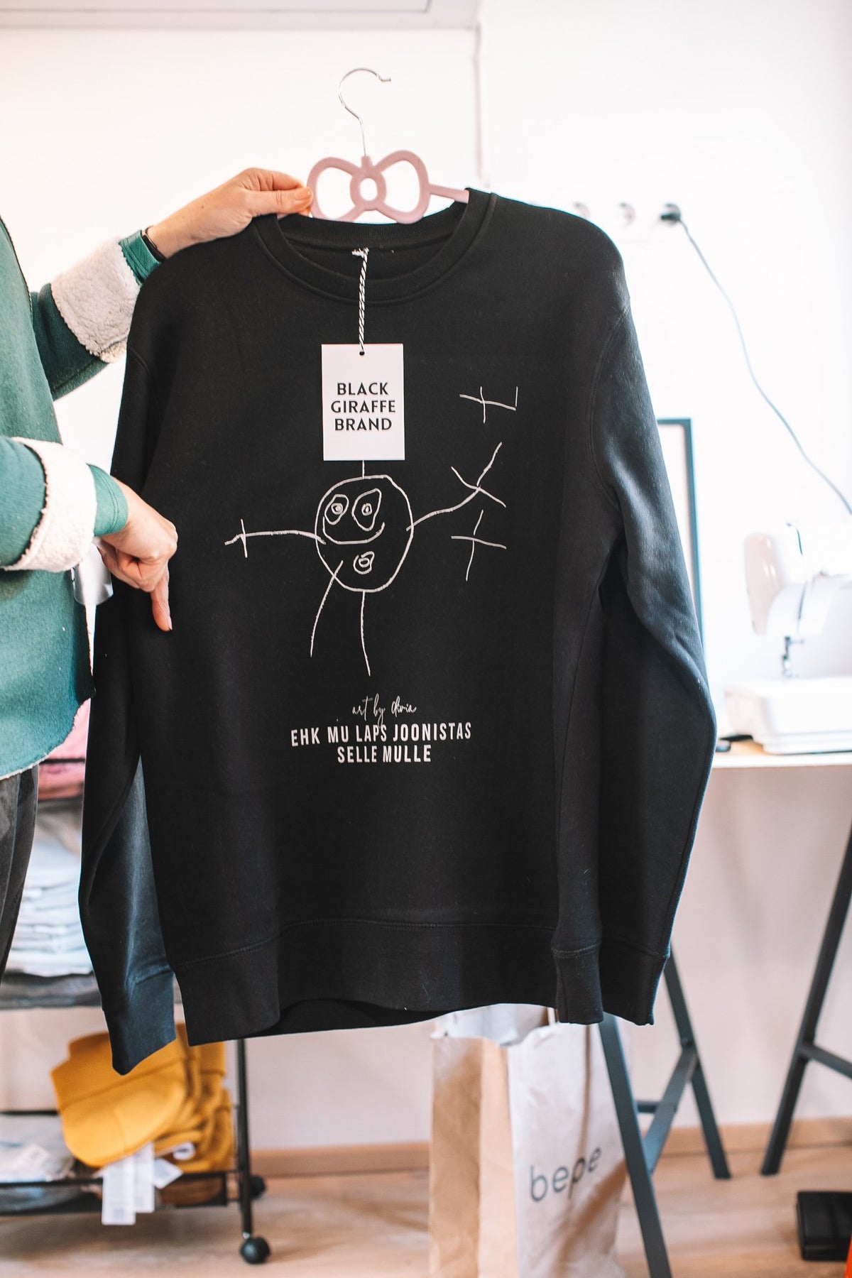 8. Black sweatshirt with custom child's artwork, Black Giraffe Brand, shown in studio setting