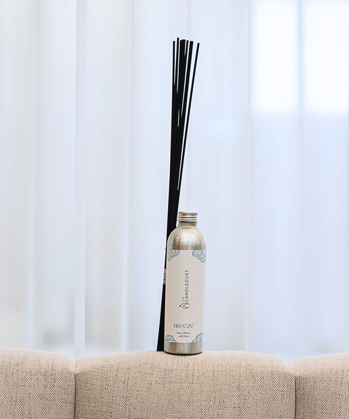 1. Candledust Breeze room diffuser refill with black fiber sticks on a beige sofa