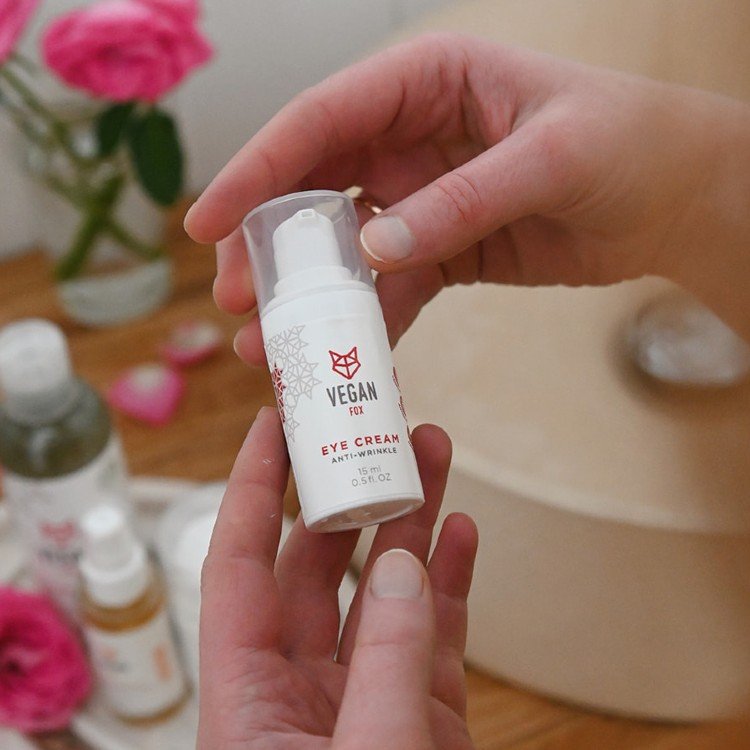 2. Vegan Fox Anti-Wrinkle Eye Cream held by woman, surrounded by skincare products and pink roses