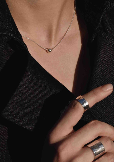 3. Women's Bubble Necklace in silver by NO MORE, styled with silver rings, highlighting sterling silver bubble design against a black outfit