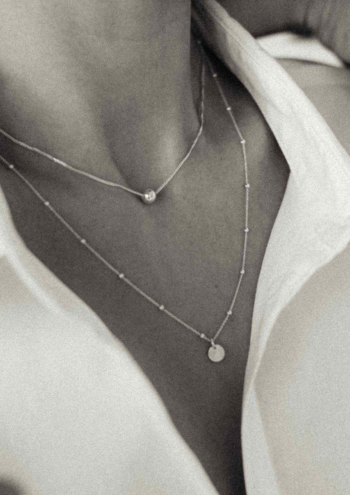 2. Women's layered look with NO MORE Bubble Necklace in silver, paired with another delicate chain, highlighting sterling silver craftsmanship