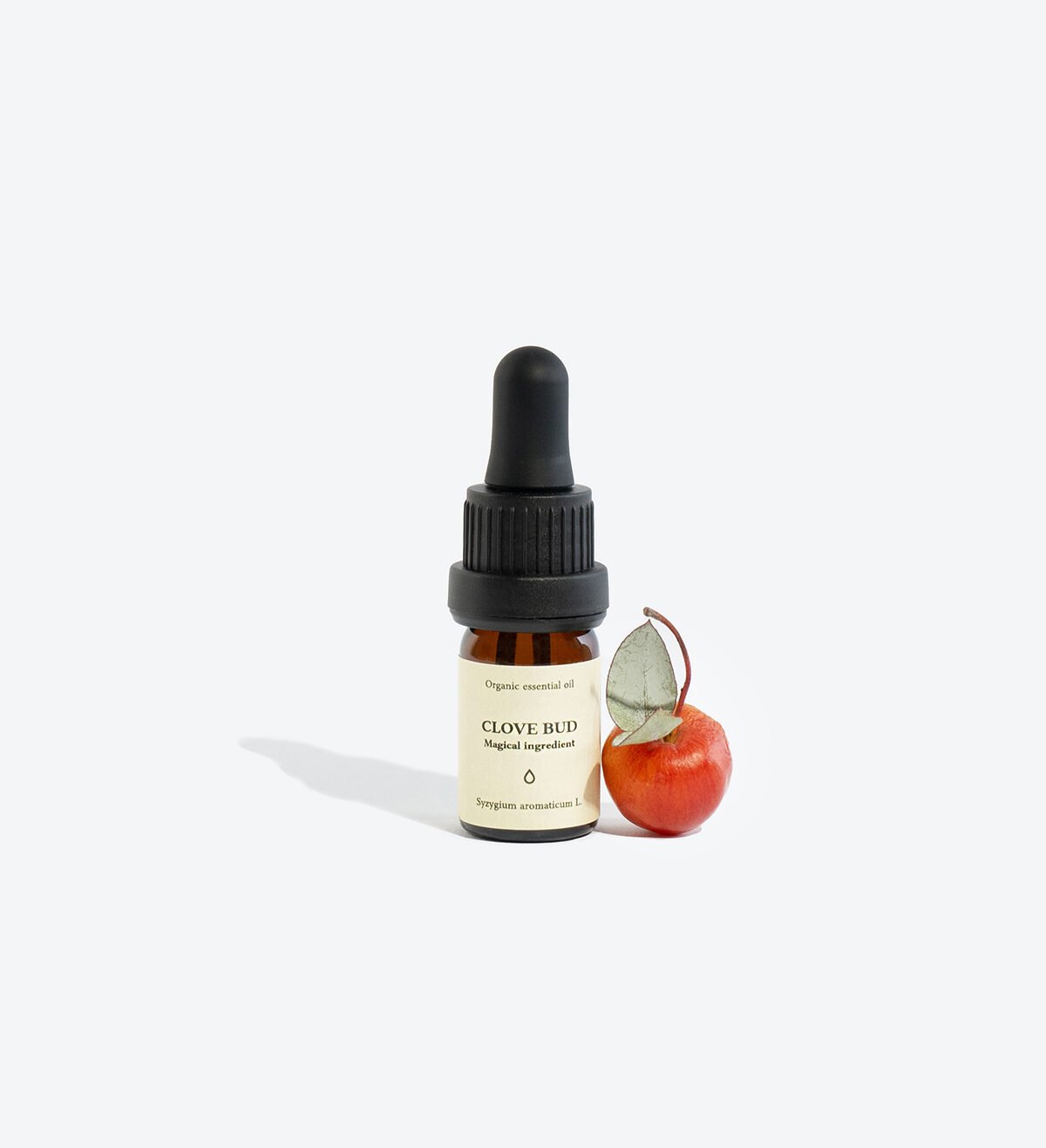 1. Smells Like Spells CLOVE BUD Essential Oil in 5 ml glass bottle with pipette, shown with a small red fruit, studio setting